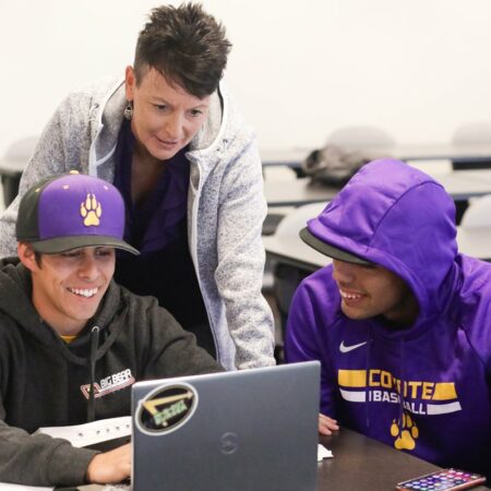 Two students with instructor near computer