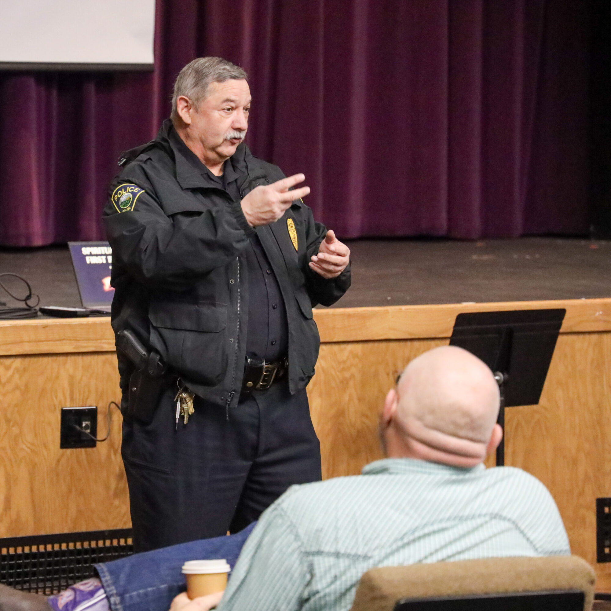 Man in police uniform holding up two fingers