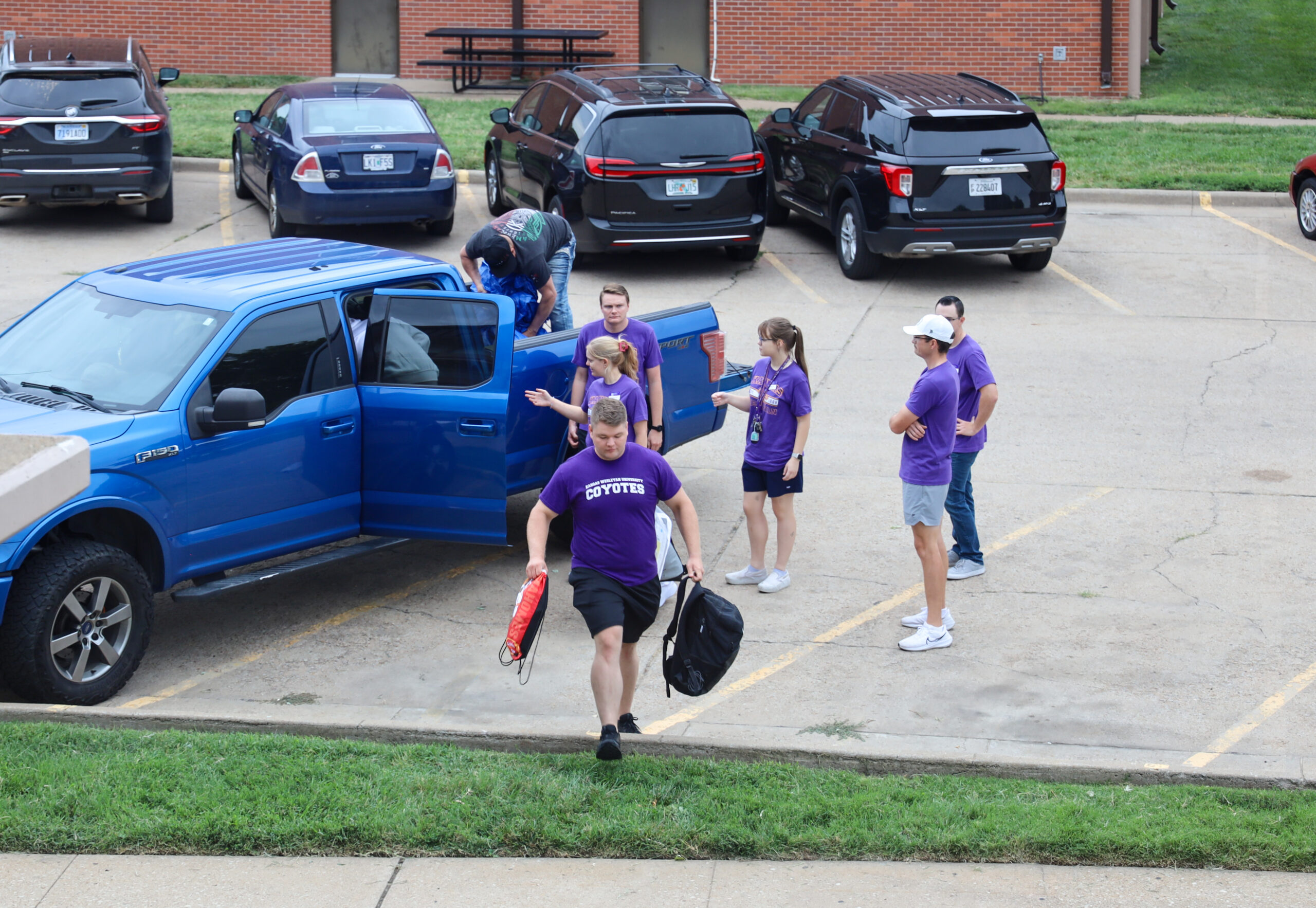 Individuals carrying belongings across parking lot