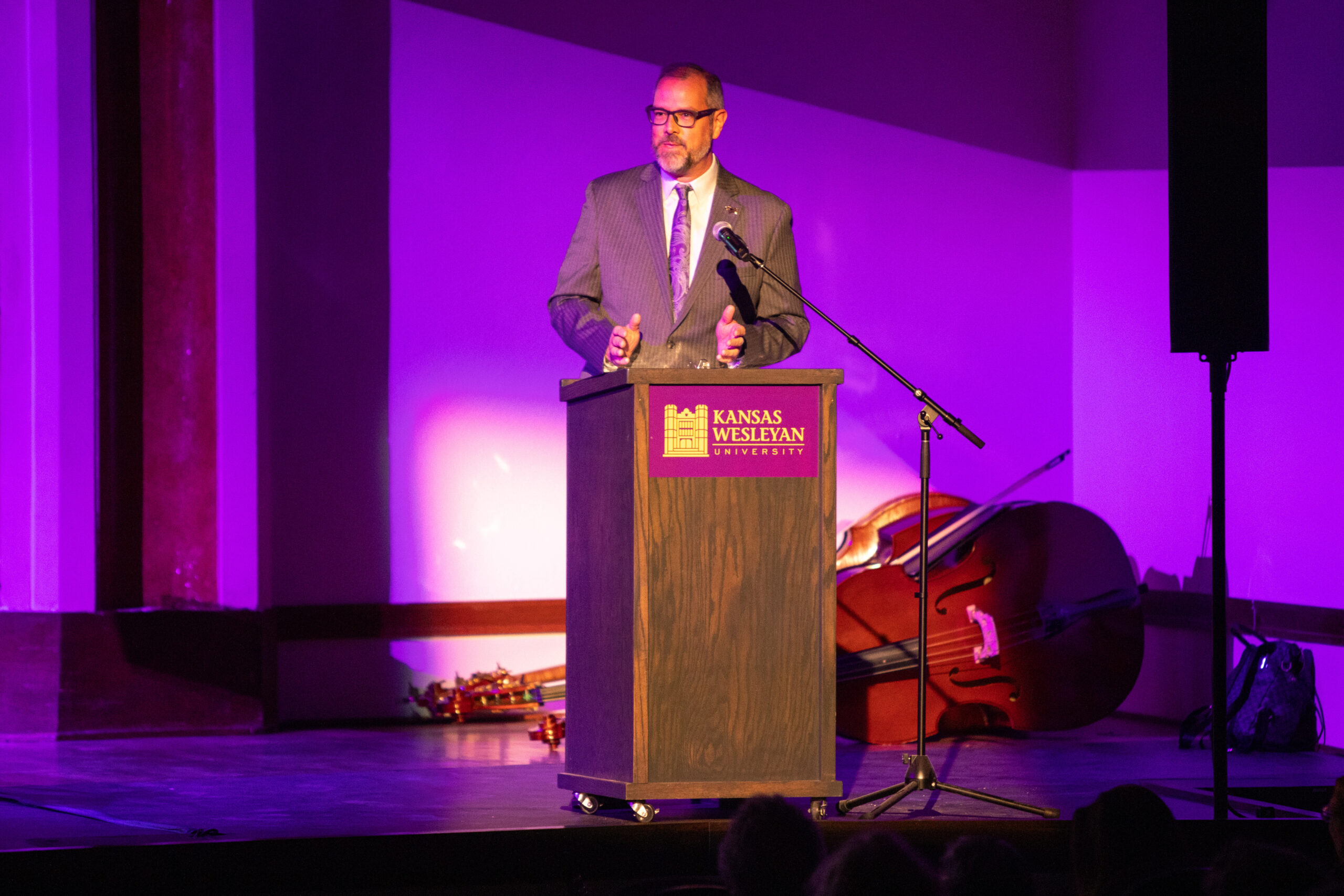 Man speaking at podium with purple light