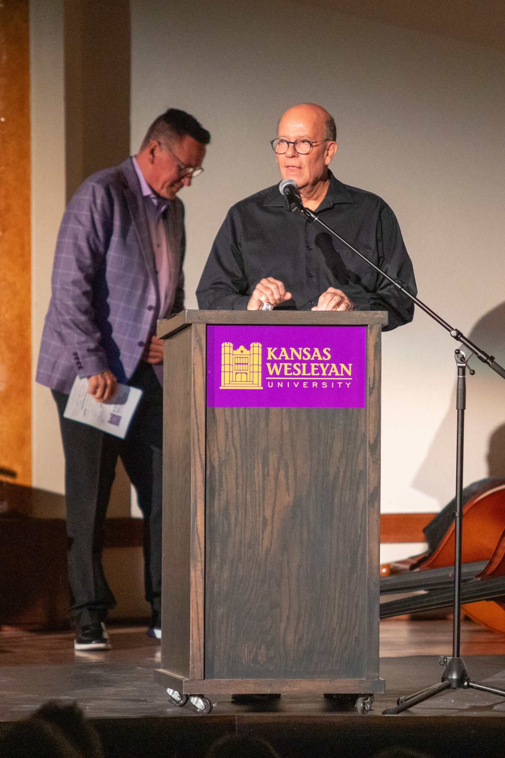 Man speaking at podium with another man pictured behind