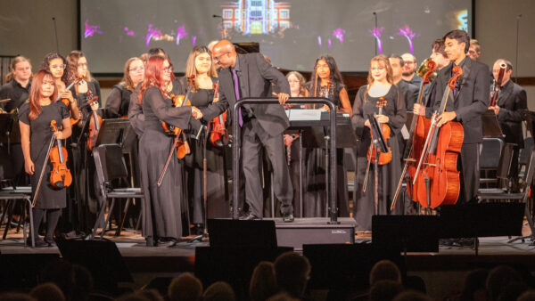 Man shaking hand of violinist, preparing to direct orchestra