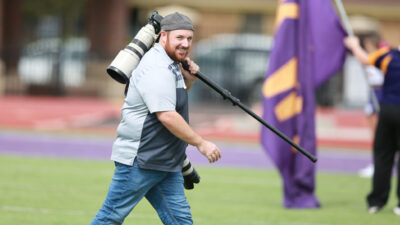 Man carrying camera on football field