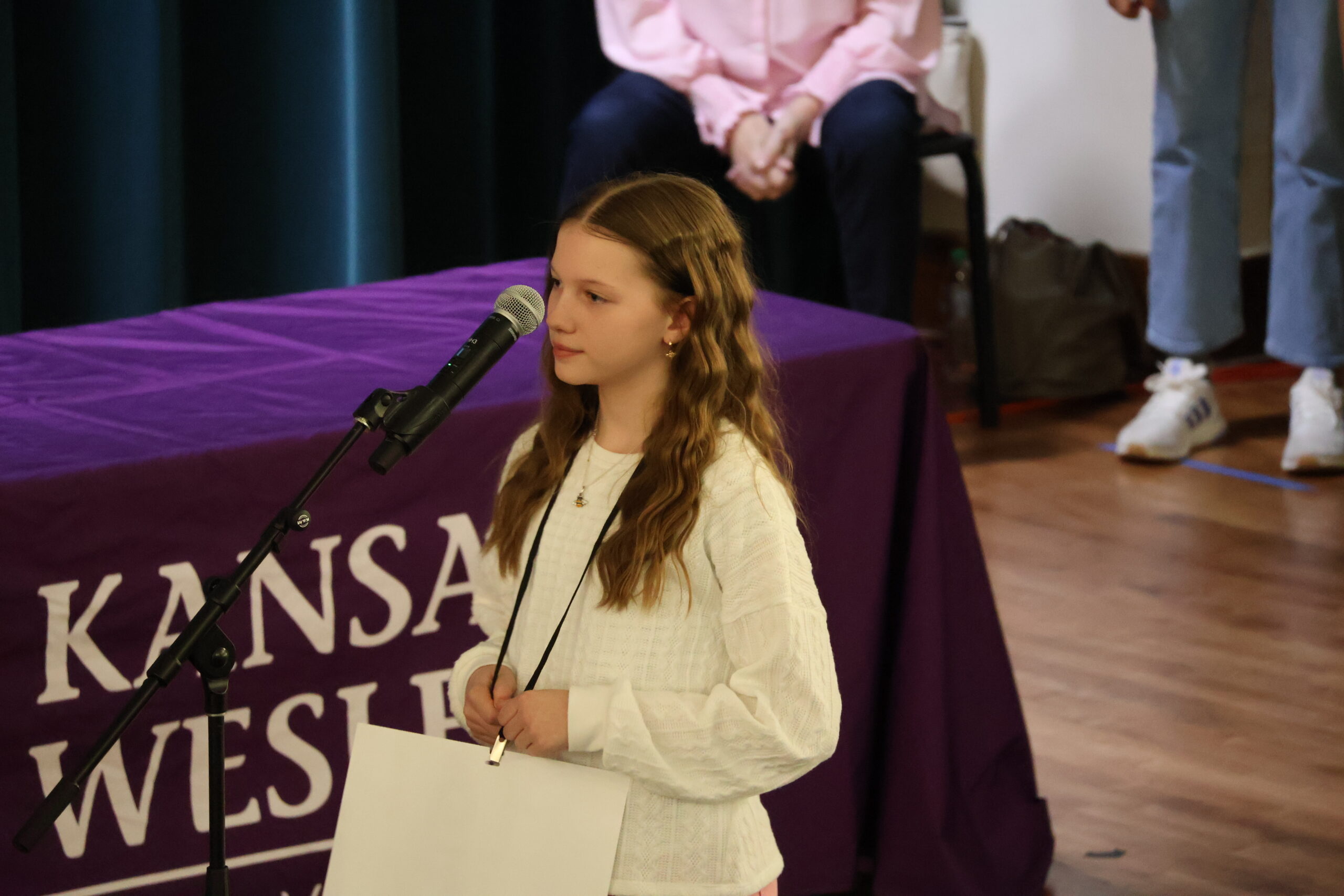 Female on stage spelling into microphone