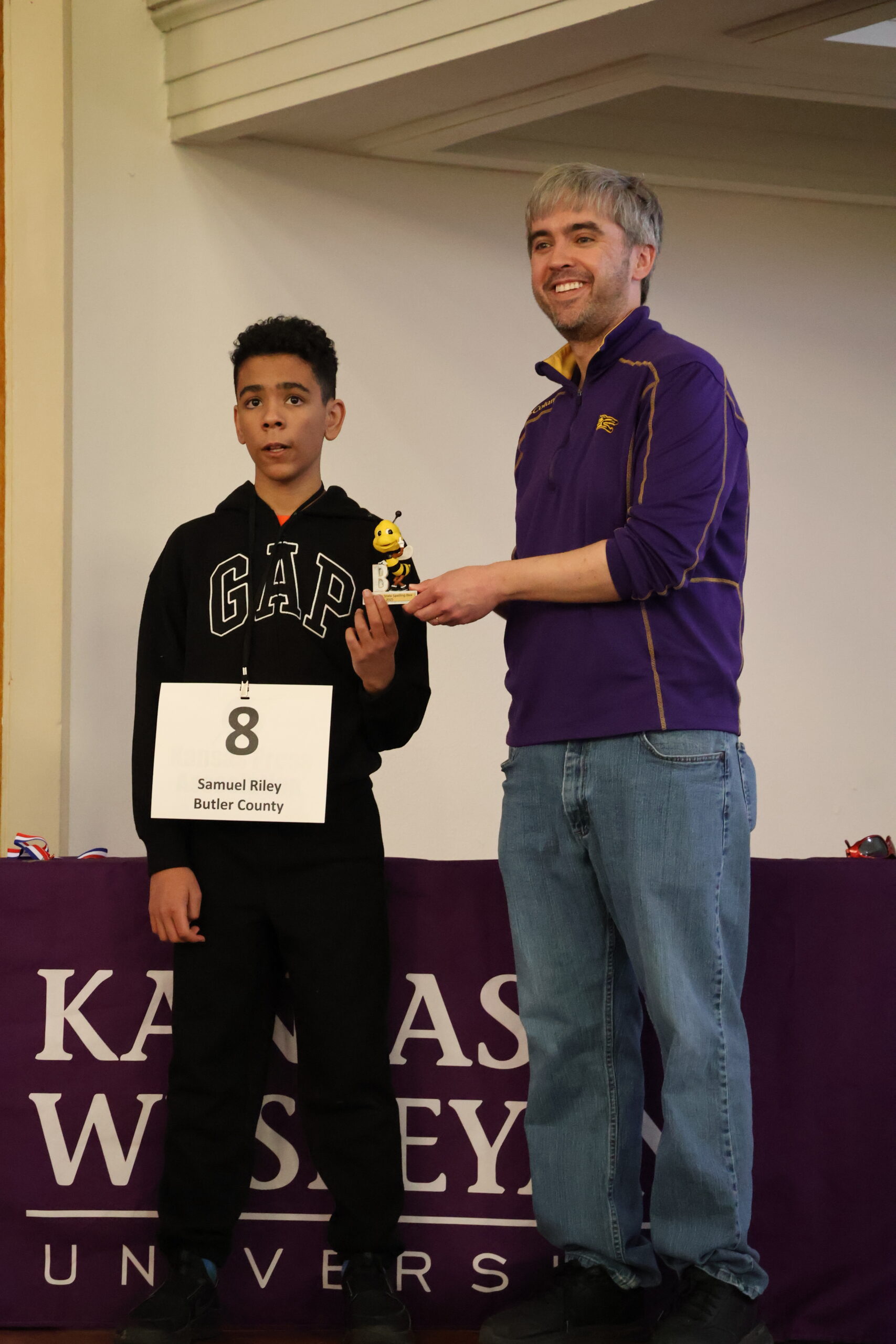 One male handing another a trophy