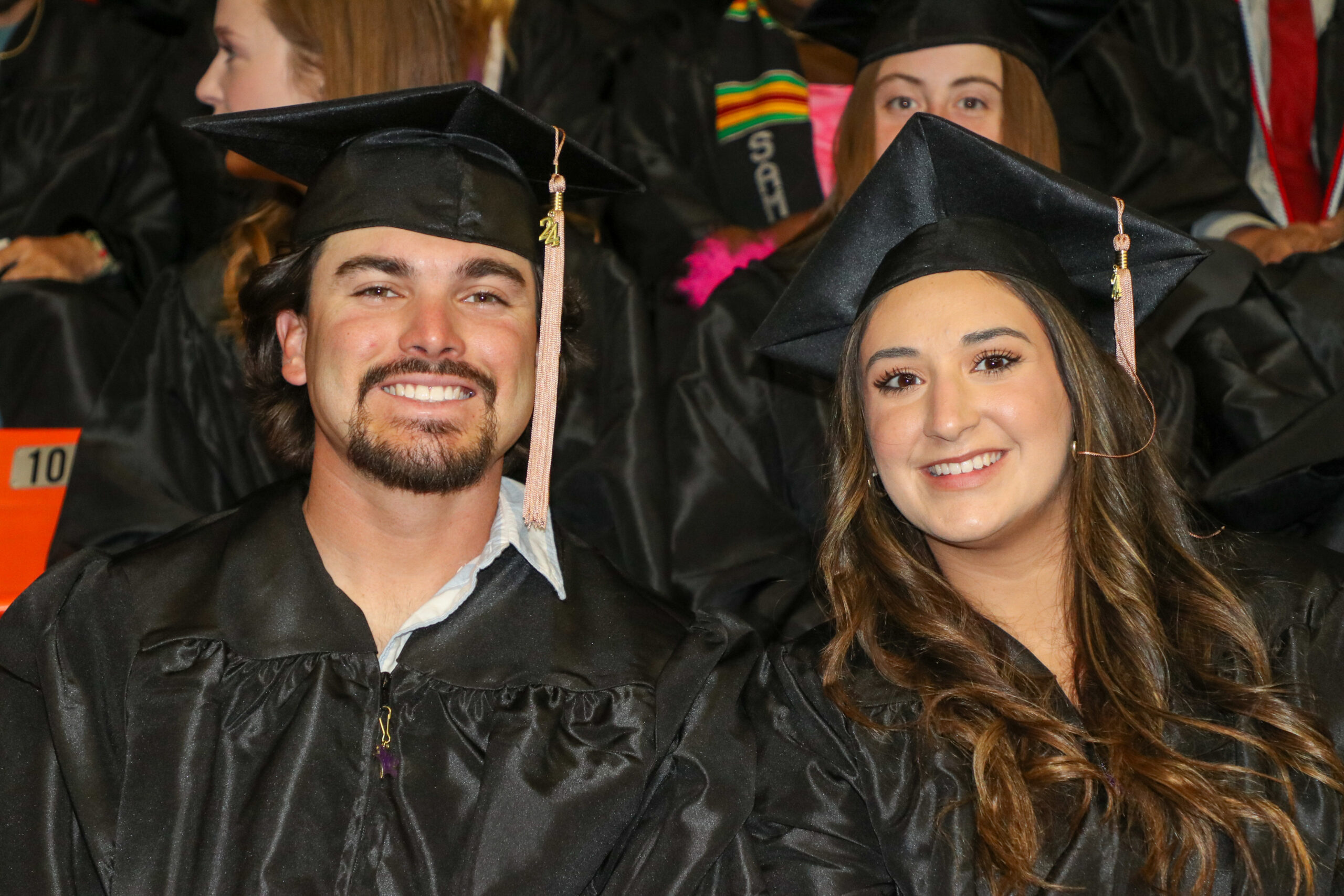 Man and woman sitting side by side in graduation attire
