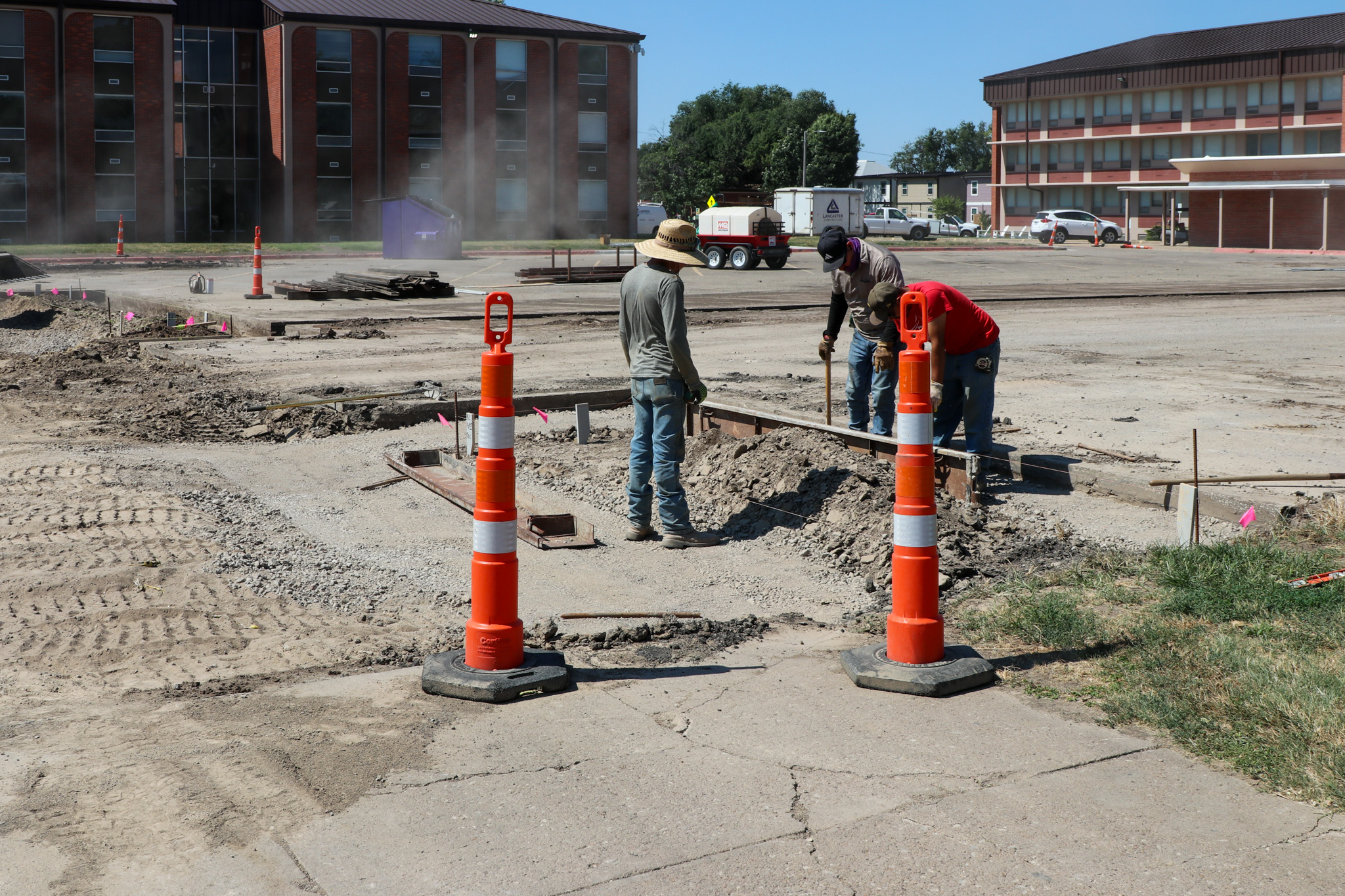Men working outside, smoothing dirt near caution cones