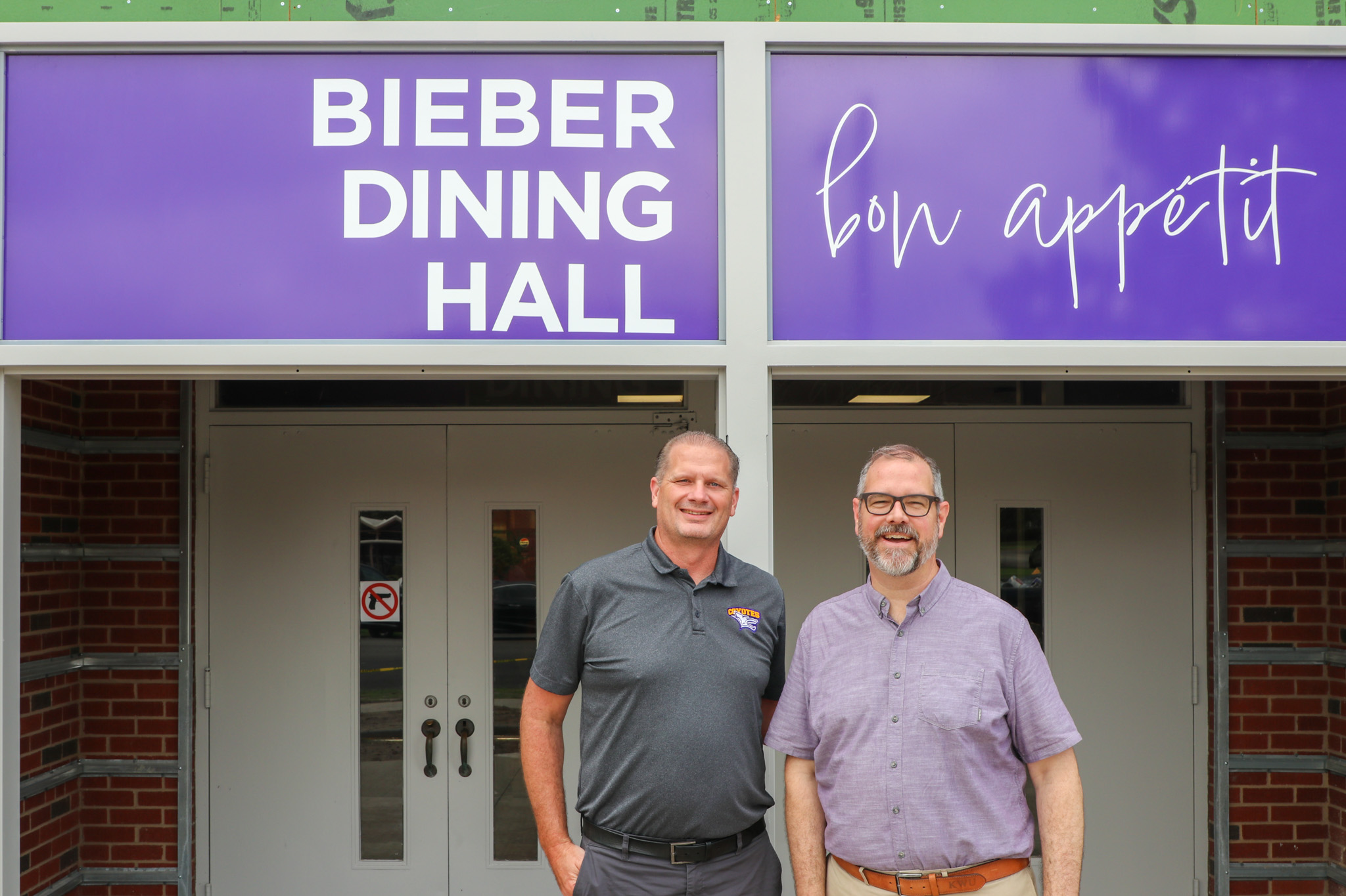 Two men standing in front of dining hall sign