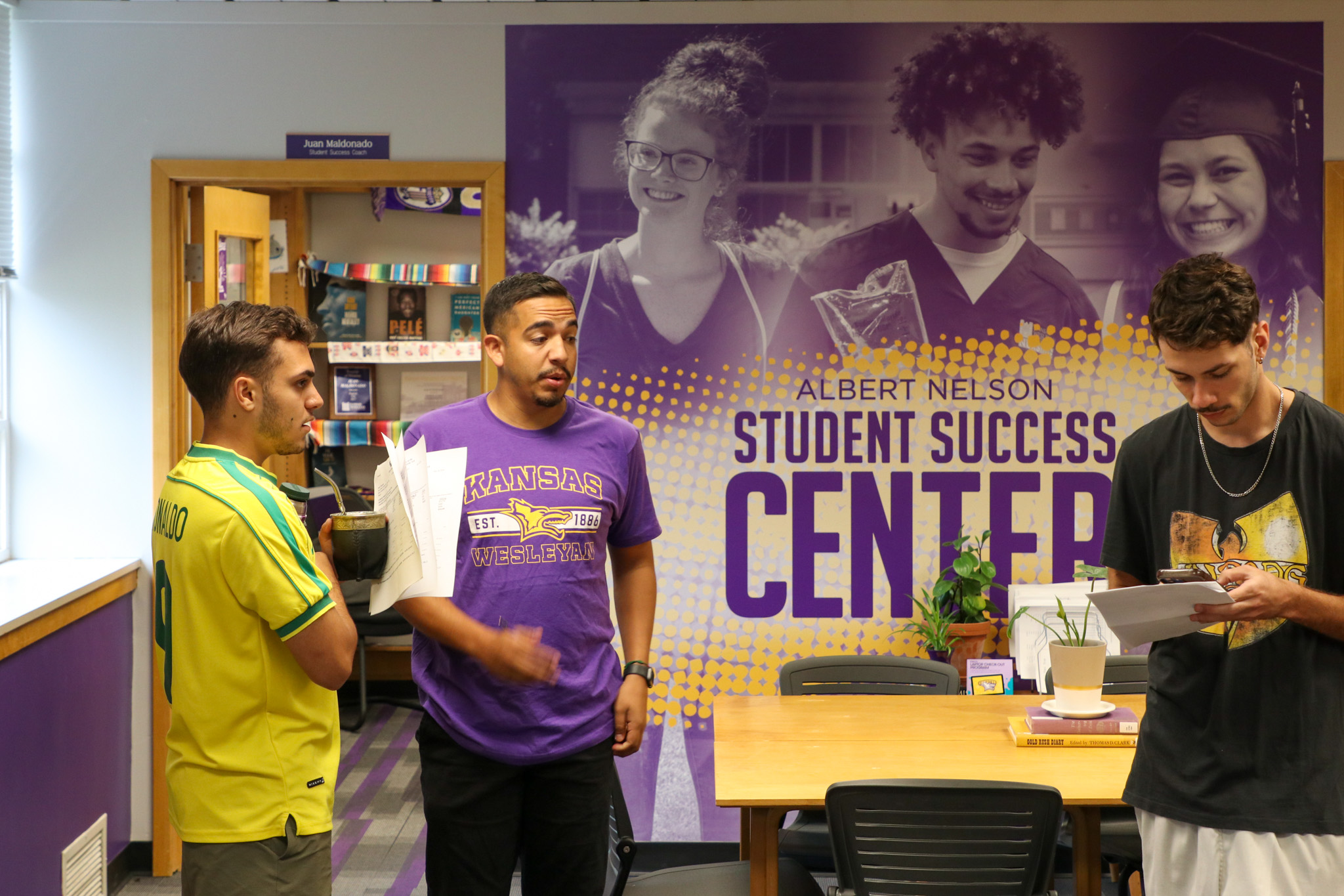 People talking in front of wall graphic for student success center