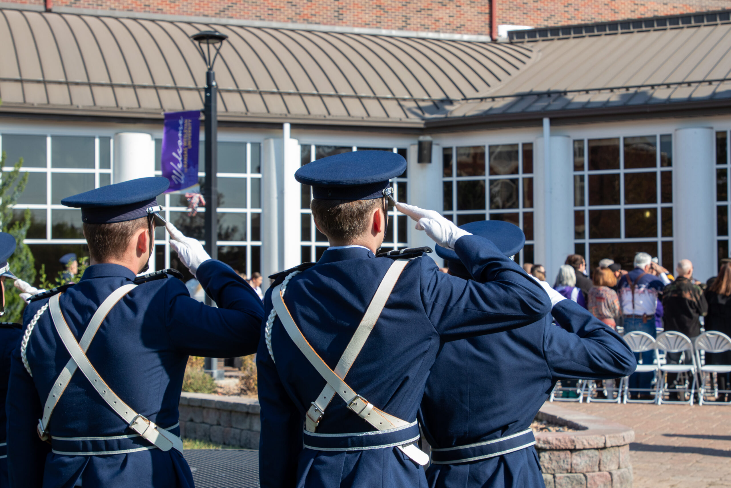 Two people in uniform saluting flag