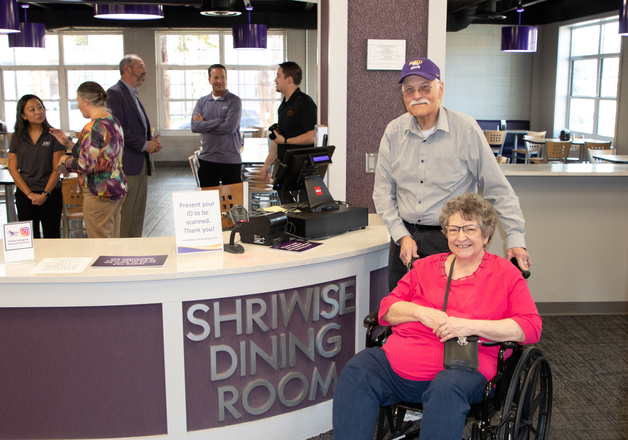 Man and woman in wheelchair next to dining room sign