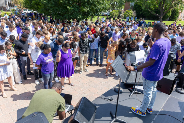 Man leading people in prayer from stage