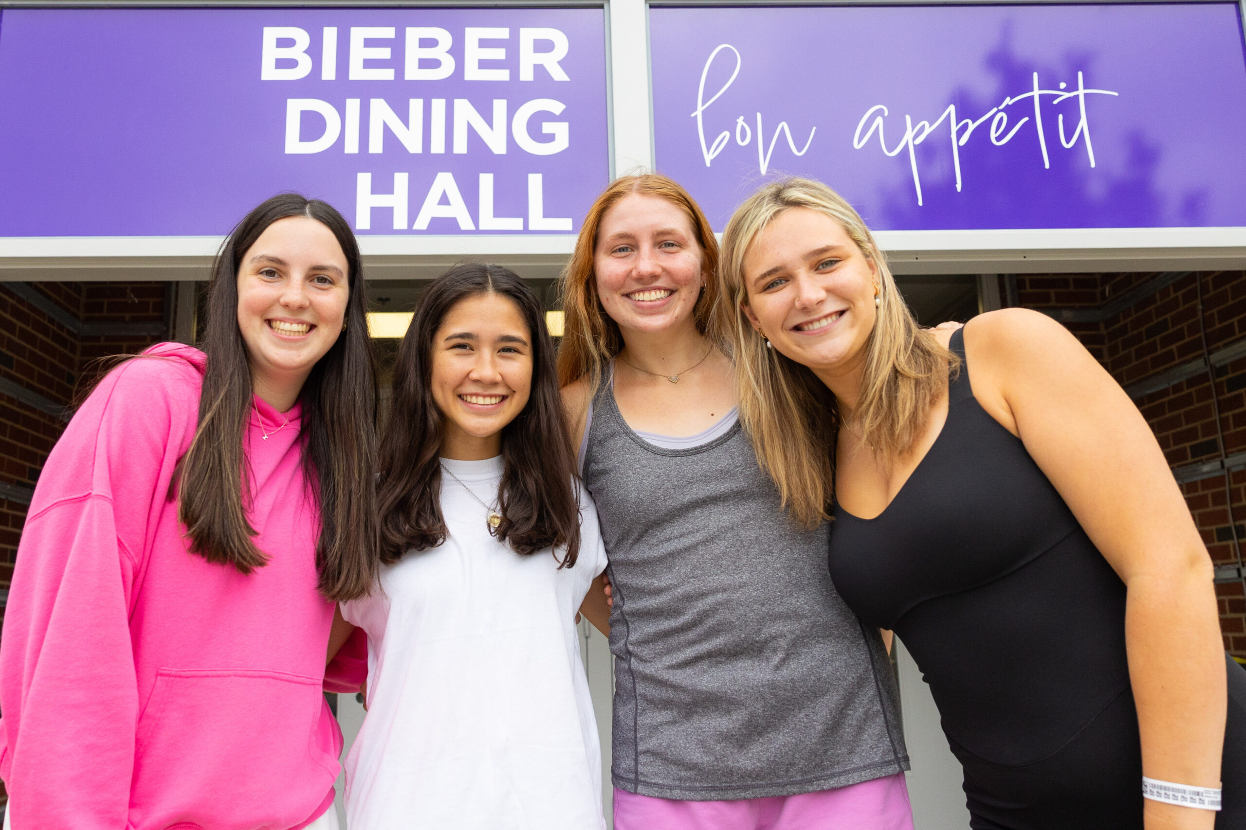 Four female students in front of dining hall sign